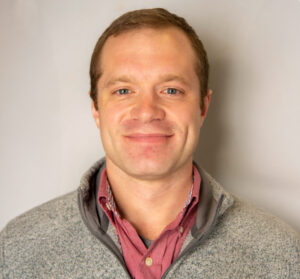 Man with brown hair and gray quarter zip