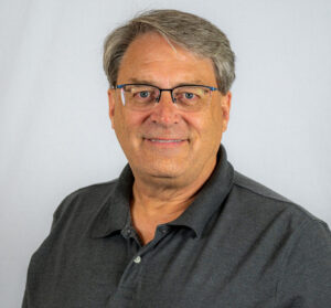 Headshot of male with black polo and glasses