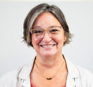 Headshot of a smiling woman, with short hair and glasses.