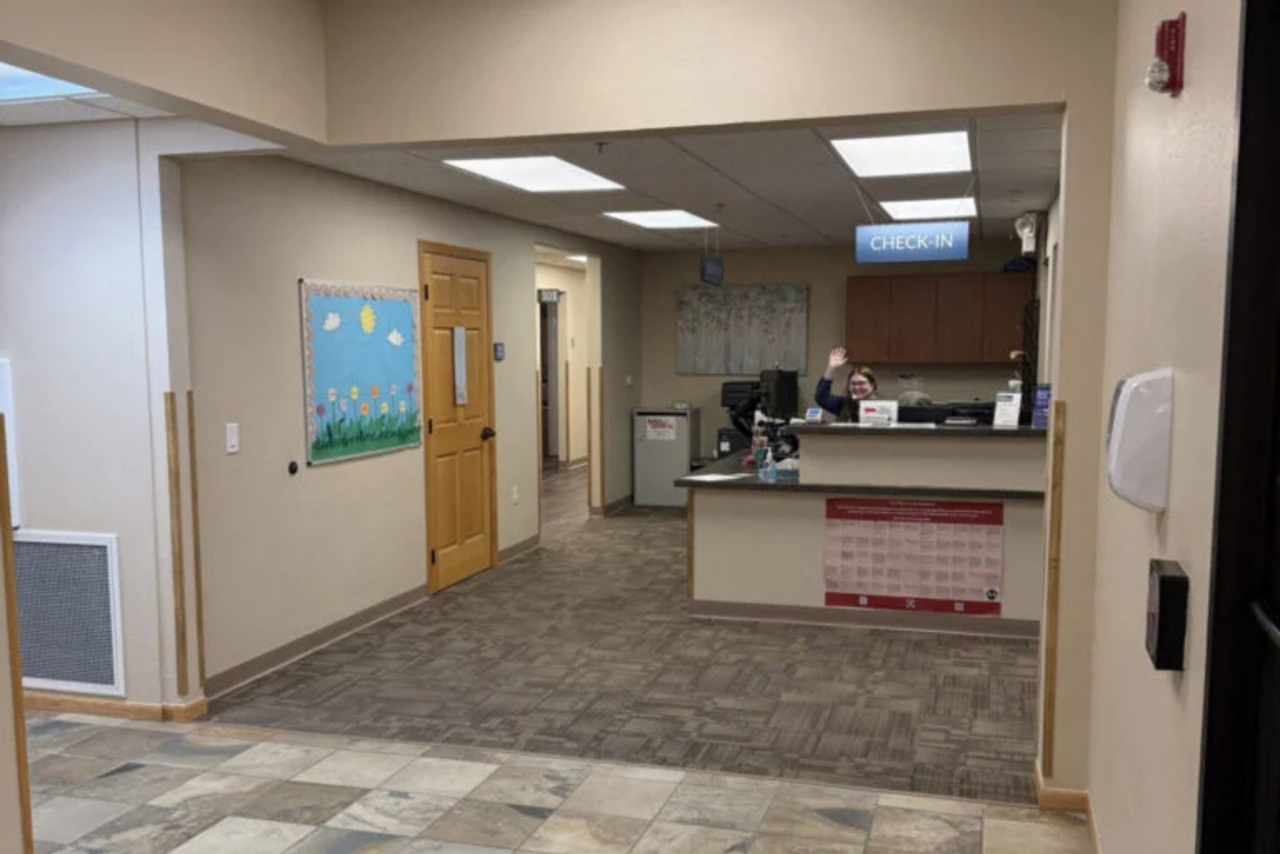 Check-In Desk with Patient Service Representative Waving Hello